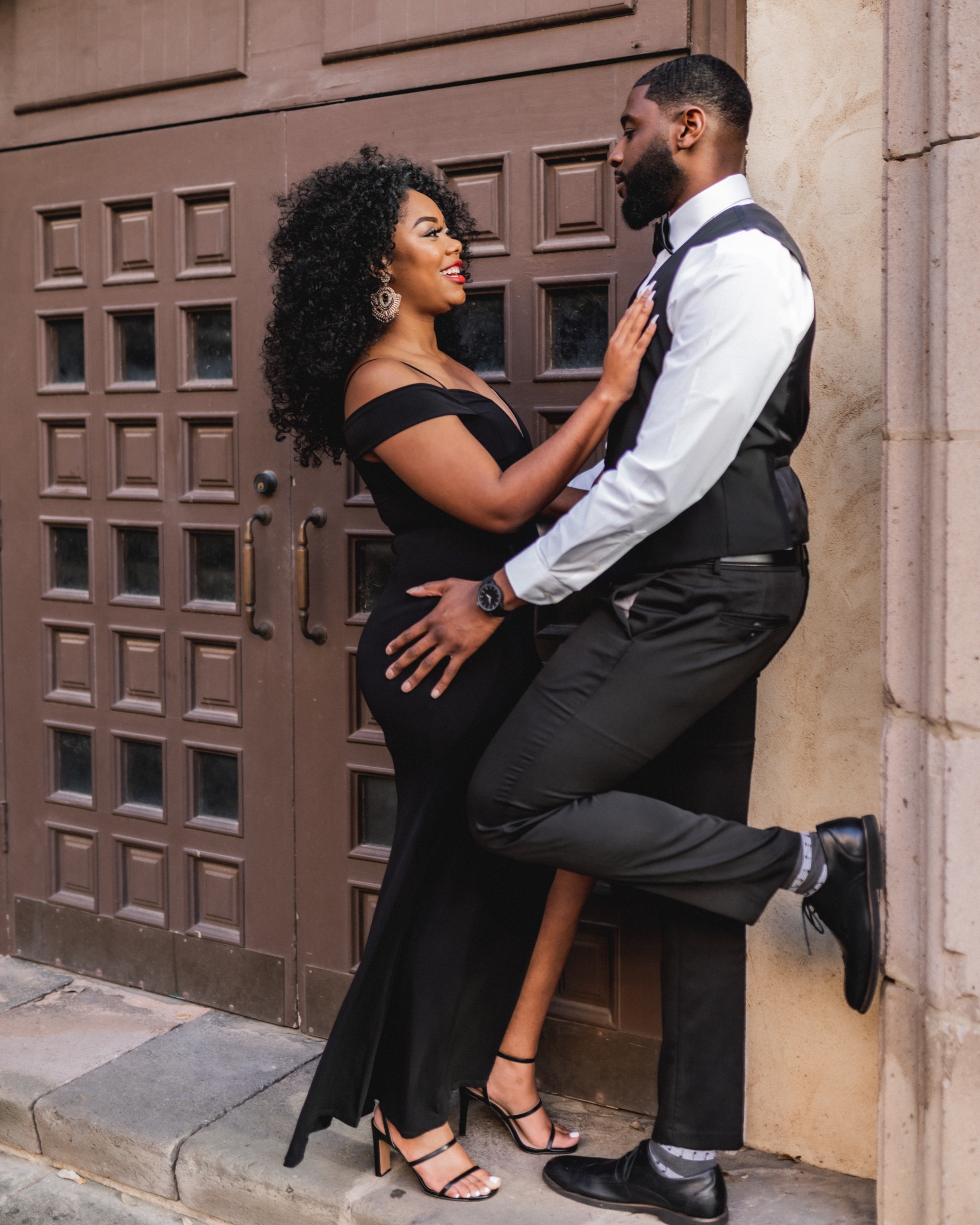 A couple posing intimately near large doors