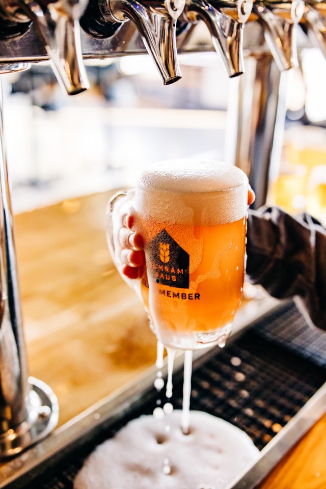 A glass of beer being overfilled at a tap