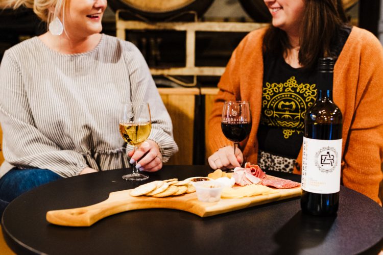 A meat and cheese board being enjoyed with wine