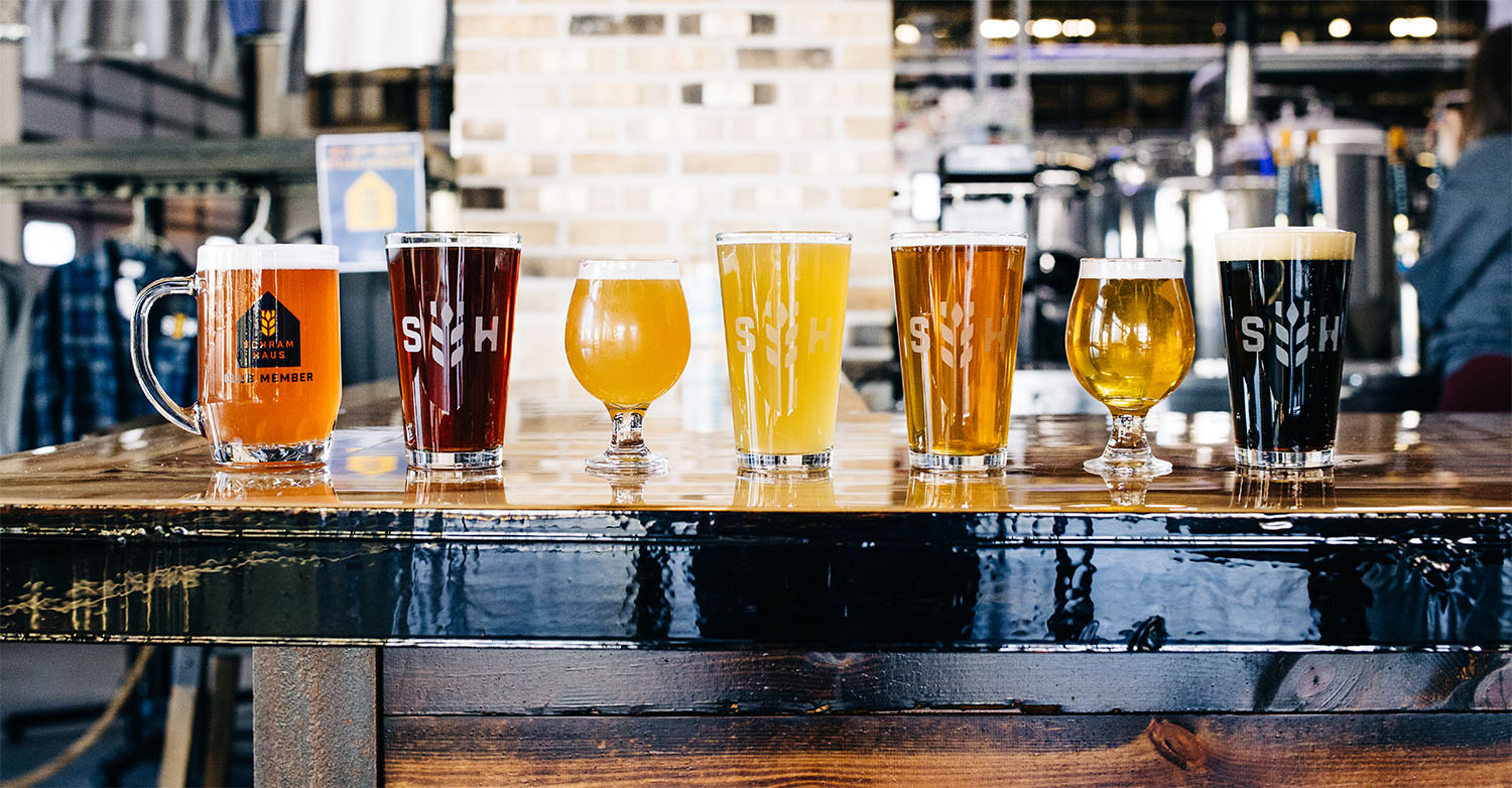 A row of different beers on a bar top