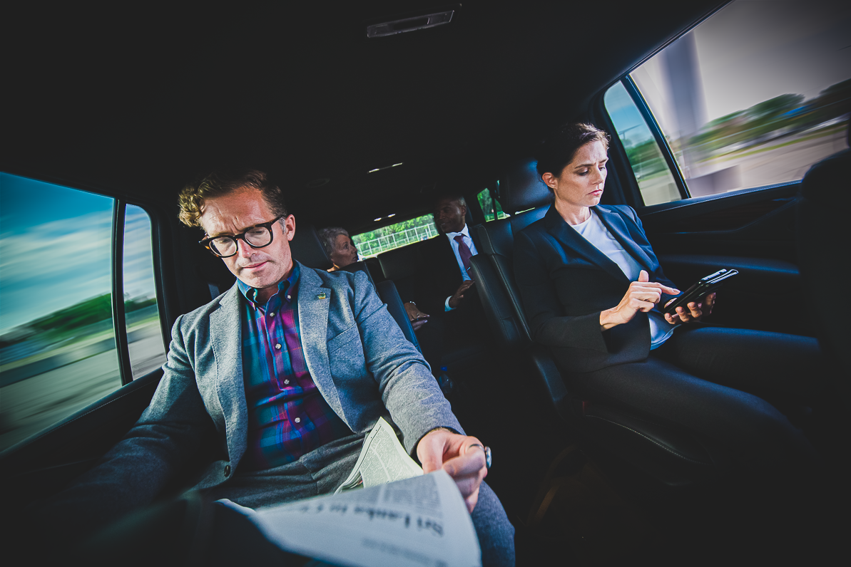 Four executives in SUV travelling between meeting locations on a roadshow.