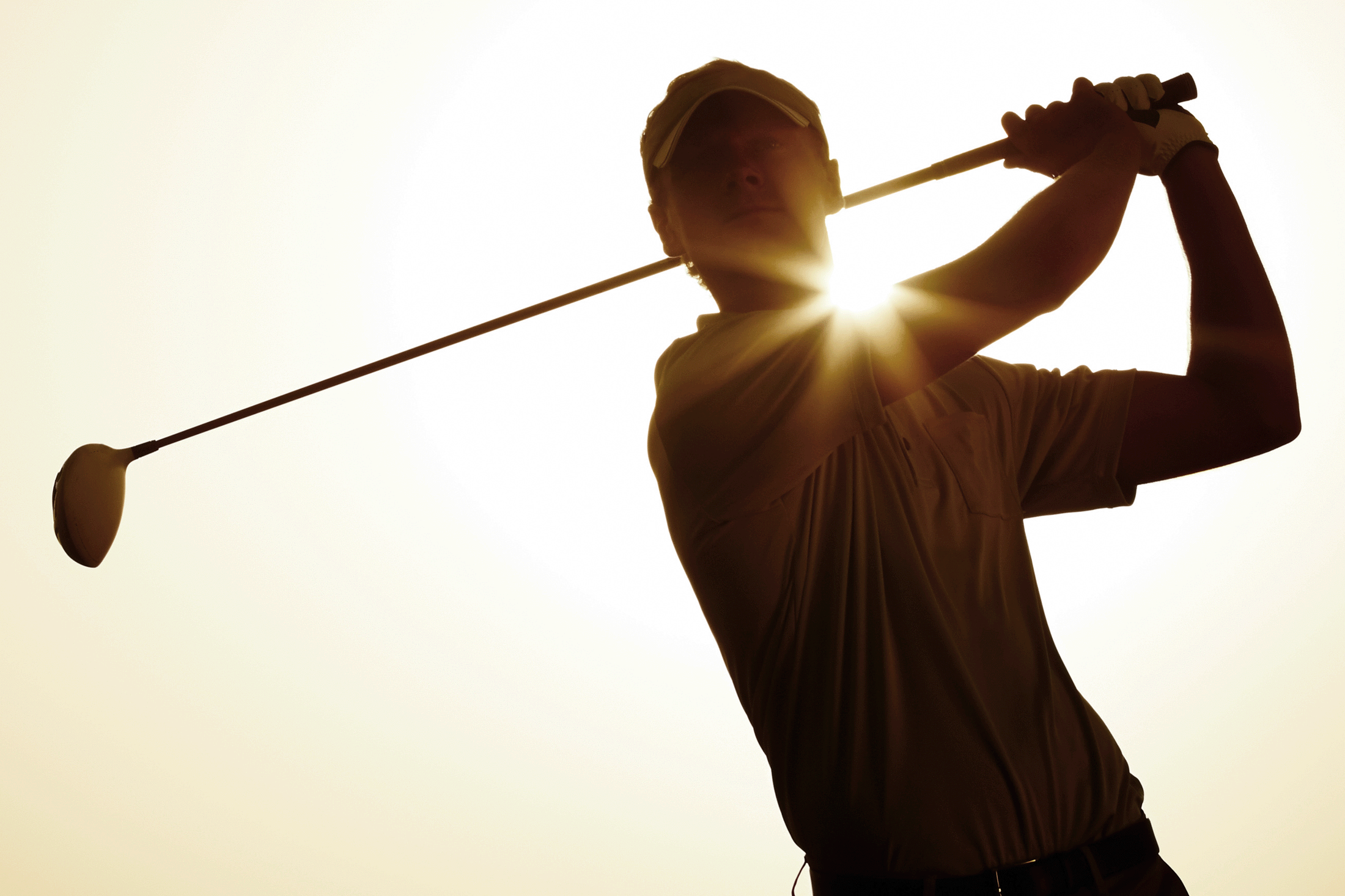 Golfer silhouetted in the sun just after taking a shot