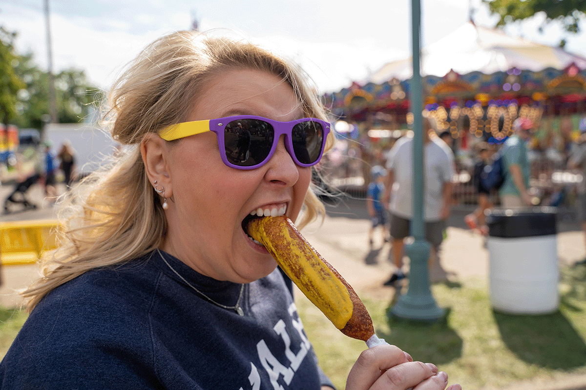Woman biting into a Pronto Pup at the Minnesota State Fair.