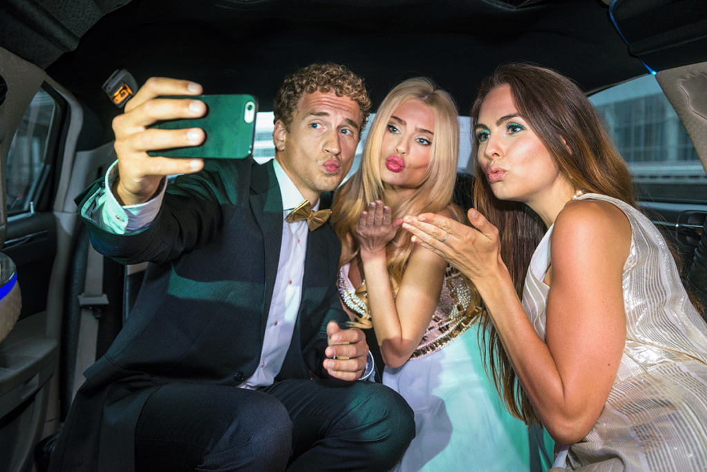 Groomsman and bridesmaids posing for a selfie in the limousine on the way to the wedding.