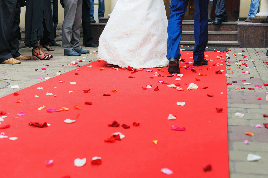 Wedding couple walking the red carpet as they enter the reception from their limousine.