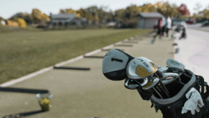 Peering down the line at the driving range as a pro golfer sets up their clubs and a bucket of balls.