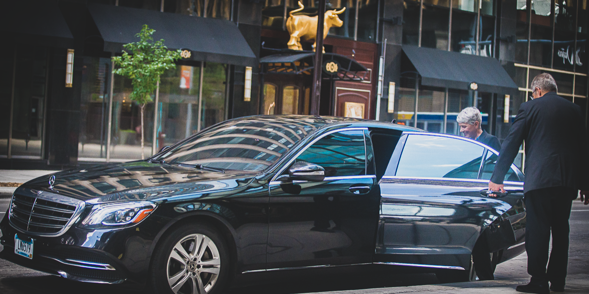 Chauffeur holding door for client as they prepare to leave downtown.