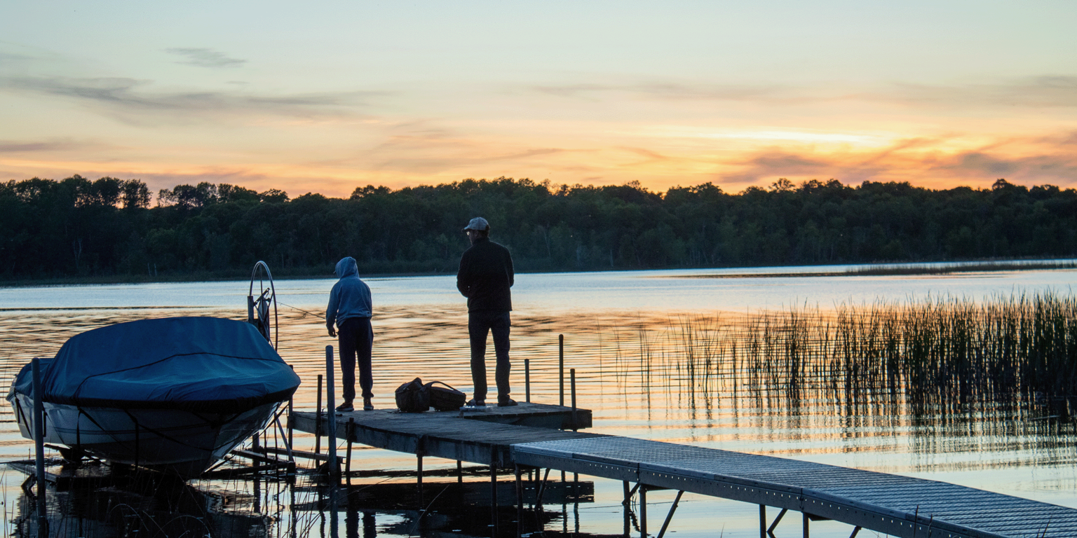 Father and son fishing off the dock at sunset at a Brainerd resort.