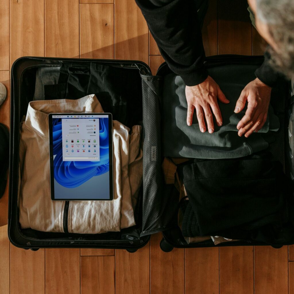 A man packs clothes and tech into his suitcase