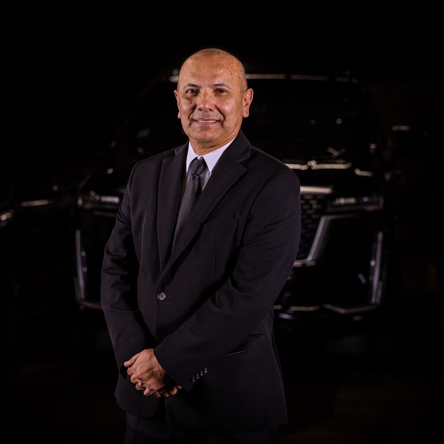 Magdiel Tapias standing proudly in front of luxury fleet cars