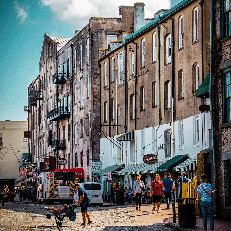 View of a busy downtown street in Savannah Georgia with cobblestone paving, tracks and narrow streets.