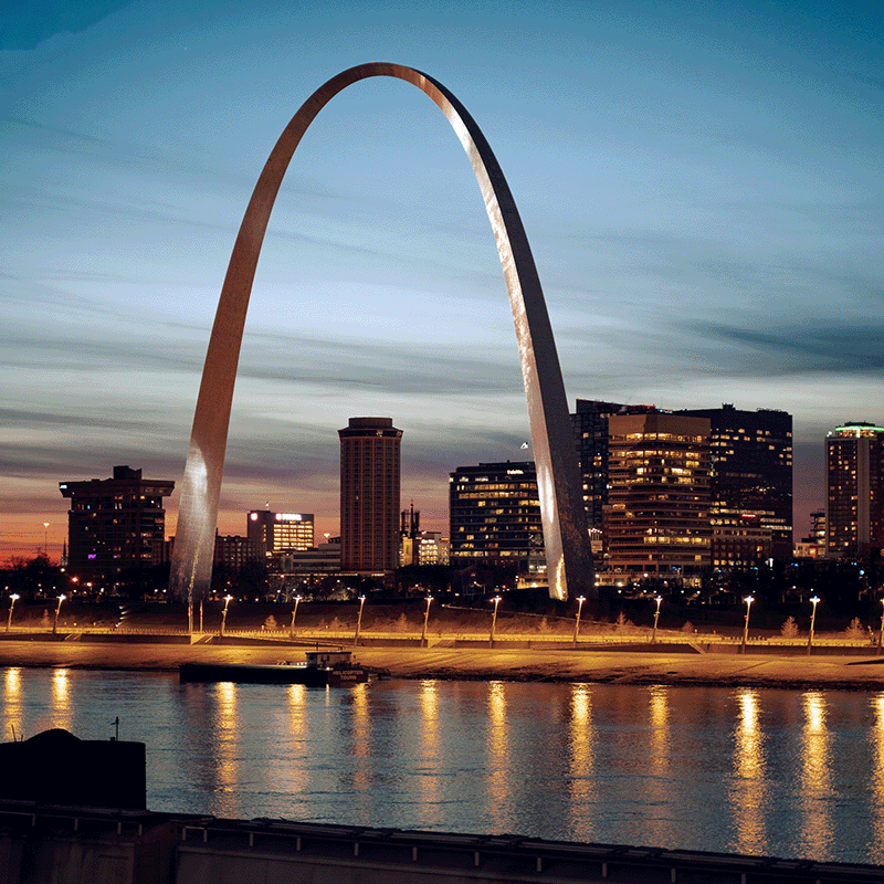 A view of the Gateway Arch over the water at sunset in St Louis Missouri.