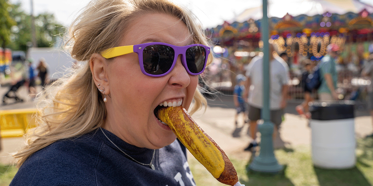 Woman biting into a Pronto Pup at the Minnesota State Fair.