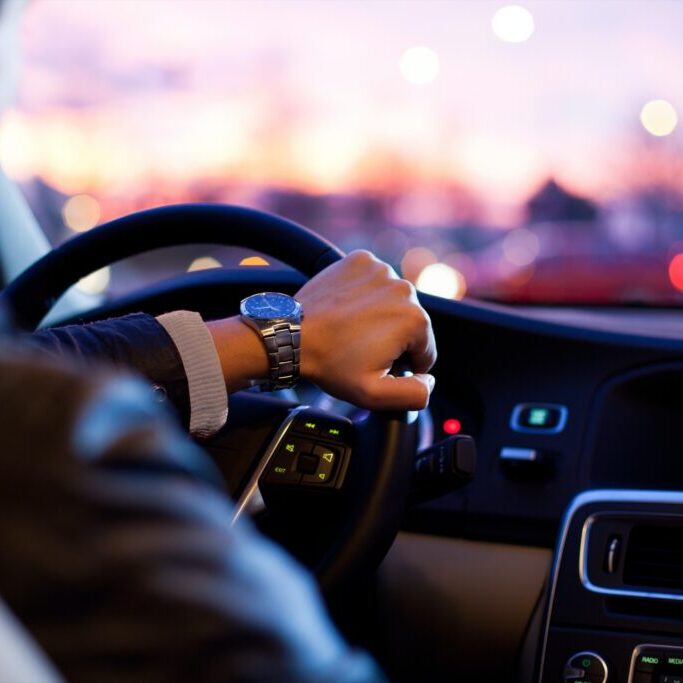 A man driving a car at sundown